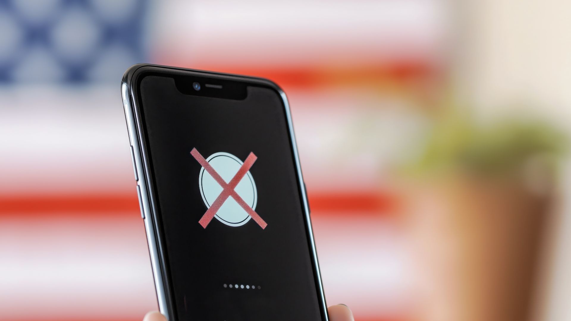 cellphone with X ban on screen. American flag in background.